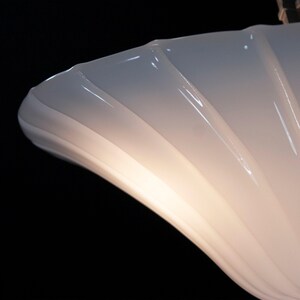 A close-up view of a curved, white light fixture with a reflective surface, creating a soft, diffused glow.