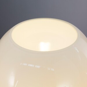 A close-up view of a white lampshade with a glowing light inside, set against a dark background.