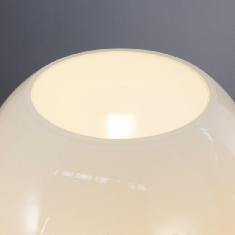 A close-up view of a white lampshade with a glowing light inside, set against a dark background.