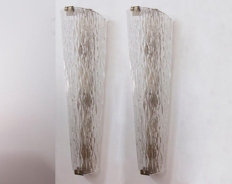 two tall, thin, and metallic wall sconces with a textured, woven design.