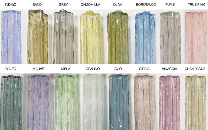 a collection of twelve glass vases, each with a unique color and pattern, arranged in two rows of six. The vases are labeled with their names, such as Indigo, Sand, Grey, Camomilla, Olive, Borotalco, Fume, True Pink, Ralto, Malve, Mela, Opalino, Avio, Cipri, Vinacia, and Champagne.