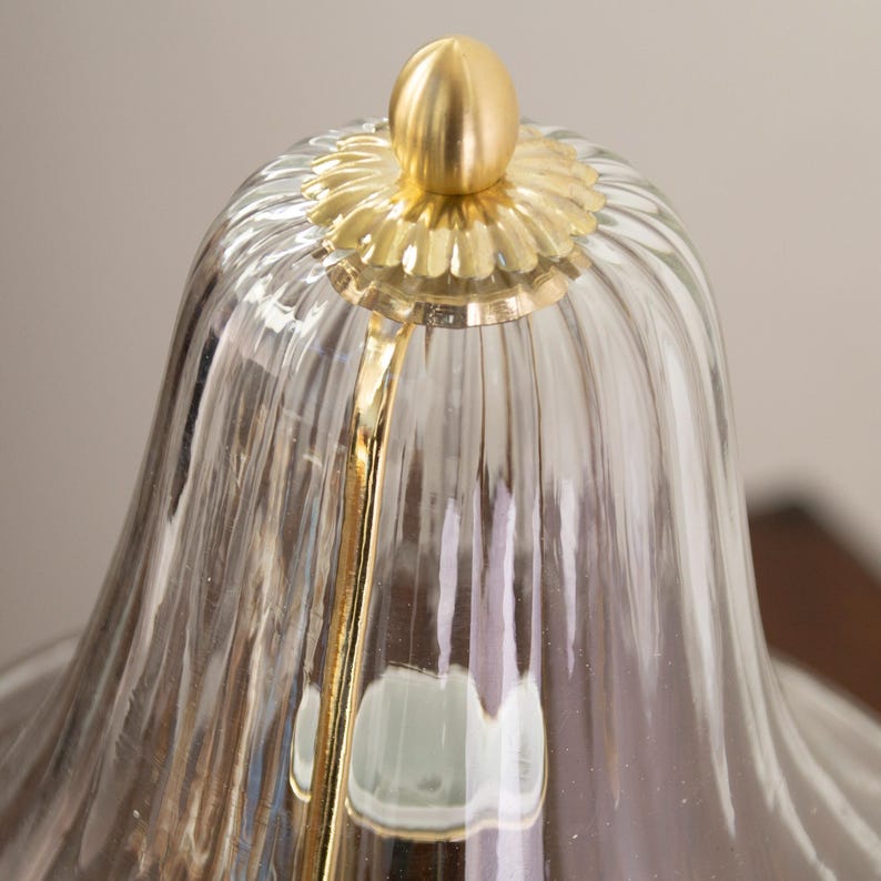 a close-up view of a glass lampshade with a gold-colored finial at the top.
