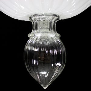 A close-up view of a clear glass vase or container with a ribbed texture, set against a black background.