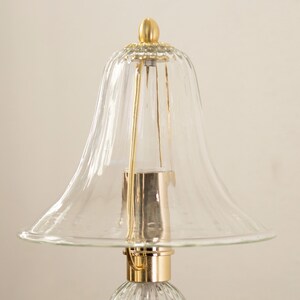 A close-up view of a clear glass lamp shade with a gold-colored metal base.