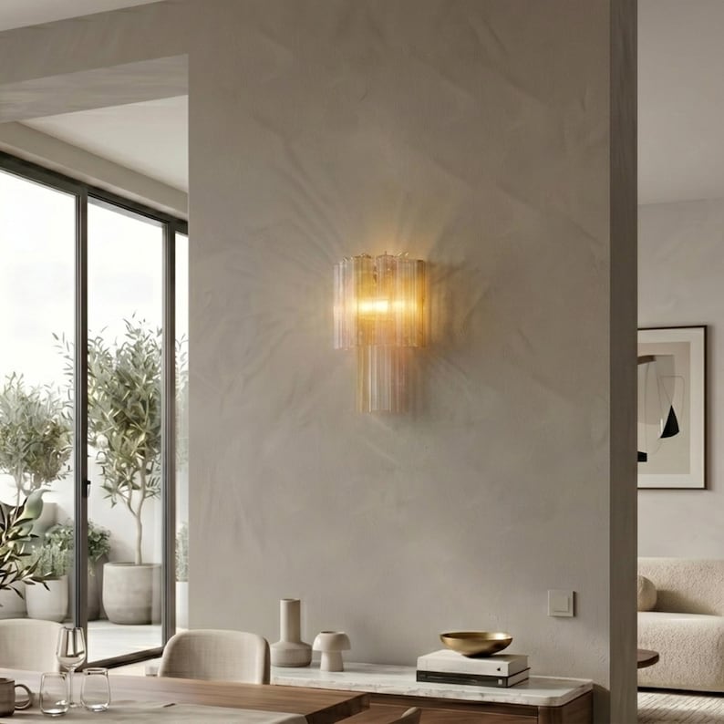 a modern and minimalist living space with a large window, a wall-mounted light fixture, and a dining table with chairs.