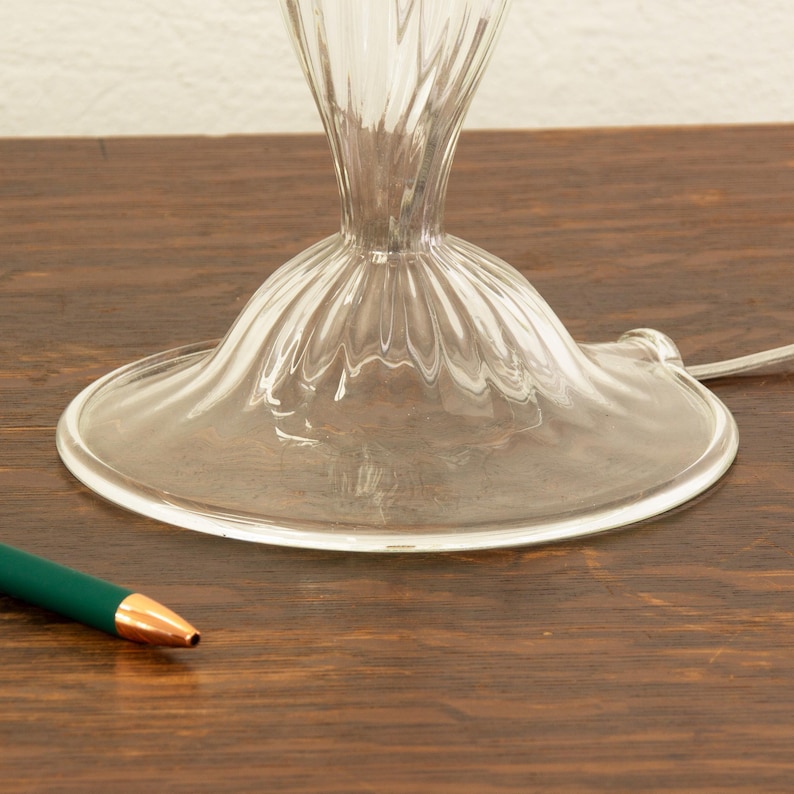 a clear glass vase with a gold rim, placed on a wooden surface next to a green pen.
