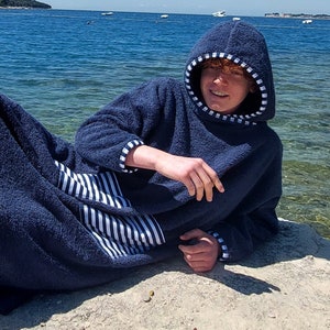 May include: A navy blue hooded towel robe with white stripes on the pocket and trim. The robe is made of soft, absorbent material and is perfect for drying off after a swim.