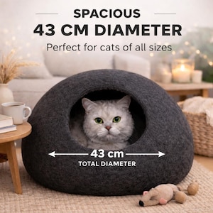 Peut inclure: Une grotte pour chat en feutre gris fonc&eacute; avec une ouverture ronde et un diam&egrave;tre de 43 cm. Le texte sur l'image indique : SPACIOUS 43 CM DIAMETER, Perfect for cats of all sizes, et 43 cm TOTAL DIAMETER. Un chat clair est visible &agrave; l'int&eacute;rieur.
