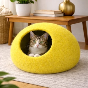 Peut inclure: Une grotte pour chat en feutre jaune vif, en forme de d&ocirc;me avec une ouverture circulaire. Un chat tigr&eacute; brun et blanc aux yeux verts est assis &agrave; l'int&eacute;rieur de la structure, regardant devant. L'ext&eacute;rieur a un aspect doux et textur&eacute;.
