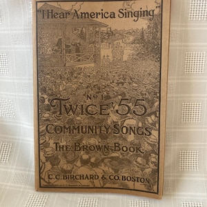 May include: A vintage book cover with a brown background and a black and white illustration of a crowd of people gathered around a stage. The title of the book is "Twice 55 Community Songs: The Brown Book" and the subtitle is "I Hear America Singing".