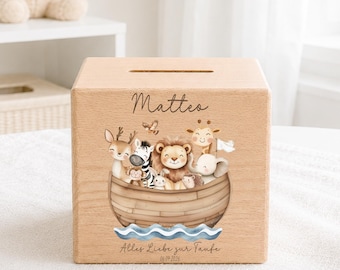 May include: A light-colored wooden money box featuring a slot on top and a printed illustration of various cartoon animals in a wooden boat. The name Matteo is printed above the animals, and the text Alles Liebe zur Taufe 06.09.2026 is below.