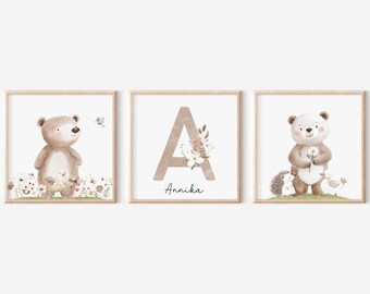 May include: Three watercolor illustrations in brown frames. The first image features a brown bear with a flower in its paw standing in a field of flowers. The second image features the letter A with a floral design and the name Annika. The third image features a white bear with a flower in its paw standing with a hedgehog and a bird.