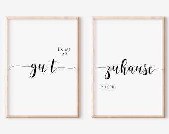 May include: Two framed prints with black text on a white background. The first print says "Es ist so gut" and the second print says "zuhause zu sein".