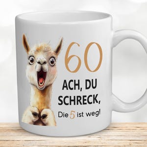 Könnte beinhalten: Weiße Keramiktasse mit einer Cartoon-Lama-Illustration und dem Text "60 ACH, DU SCHRECK, Die 5 ist weg!"