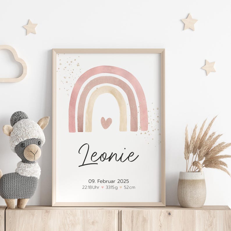 Peut inclure: Une impression d'arc-en-ciel aquarelle avec un sch&eacute;ma de couleurs rose, beige et marron. L'arc-en-ciel a un petit c&oelig;ur au centre. L'impression comprend le nom Leonie, la date 09. Februar 2025, et l'heure 22:18Uhr, le poids 3315g, et la longueur 52cm.