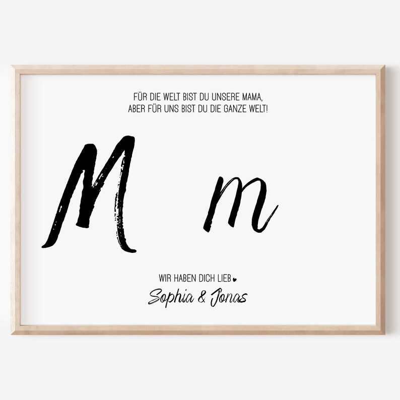 Puede incluir: Una impresi&oacute;n enmarcada con fondo blanco presenta el texto "F&Uuml;R DIE WELT BIST DU UNSERE MAMA, ABER F&Uuml;R UNS BIST DU DIE GANZE WELT!" y "WIR HABEN DICH LIEB." Se muestran dos letras "M" negras en cursiva. Tambi&eacute;n se incluyen los nombres "Sophia & Jonas".