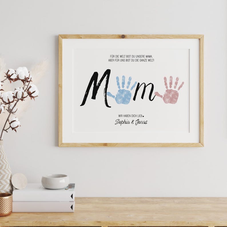 Puede incluir: Impresi&oacute;n enmarcada con la palabra "Mom" en escritura negra, huellas de manos azules y rosas, y el texto: "Para el mundo eres nuestra mam&aacute;, pero para nosotros eres el mundo entero! Te queremos. Sophia & Jonas."