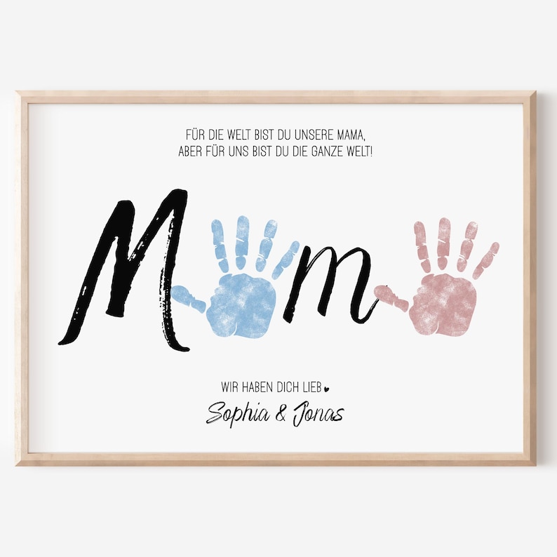 Puede incluir: Una impresi&oacute;n enmarcada con la palabra "Mom" en escritura negra, con huellas de manos azules y rosas. La impresi&oacute;n incluye texto en alem&aacute;n y los nombres "Sophia & Jonas" en cursiva, todo sobre un fondo blanco.