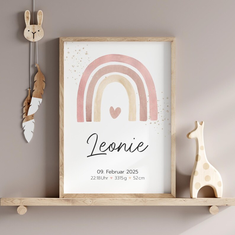 Peut inclure: Une impression d'arc-en-ciel aquarelle avec un sch&eacute;ma de couleurs rose, beige et marron. L'arc-en-ciel a un petit c&oelig;ur au centre. L'impression comprend le nom "Leonie", la date "09. Februar 2025" et l'heure "22:18 Uhr" ainsi que le poids "3315 g" et la longueur "52 cm".