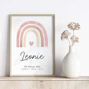 Peut inclure: Un arc-en-ciel aquarelle rose, beige et blanc avec un petit c&oelig;ur au centre. Le texte "Leonie" est sous l'arc-en-ciel, suivi de la date "09. Februar 2025", de l'heure "22:18Uhr", du poids "3315g" et de la taille "52cm".