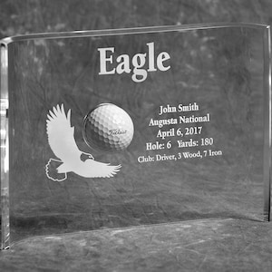 May include: A clear acrylic plaque with an engraved eagle and golf ball. The plaque reads "Eagle", "John Smith", "Augusta National", "April 6, 2017", "Hole: 6 Yards: 180", and "Club: Driver, 3 Wood, 7 Iron".