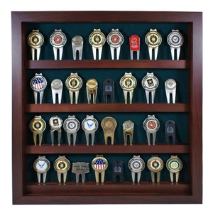 May include: A wooden display case with a green felt background, showcasing a collection of 24 golf ball divot tools. Each tool features a different military branch emblem, including the Army, Navy, Air Force, Marines, and Coast Guard.