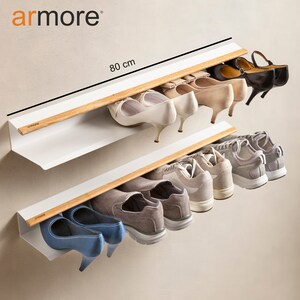 Op de afbeelding: Een wit, aan de muur gemonteerd schoenenrek met twee planken en houten rails. Het rek is 80 cm breed en biedt ruimte voor verschillende soorten schoenen, waaronder sneakers, hakken en ballerina's.