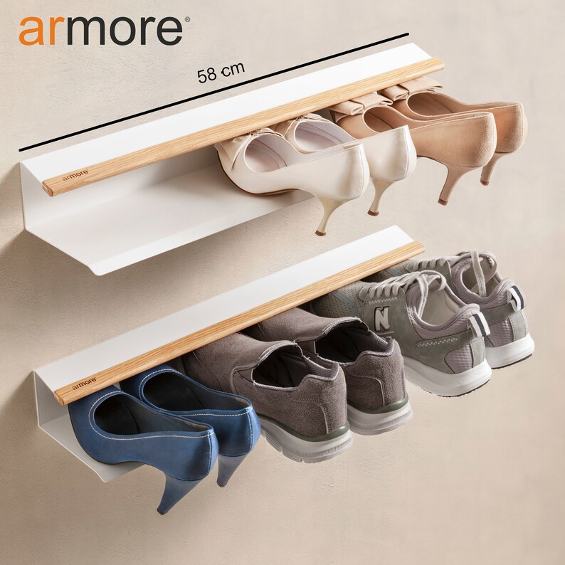 Op de afbeelding: Een wit, aan de muur gemonteerd schoenenrek met twee planken en een houten rail. Het rek is 58 cm lang en kan verschillende soorten schoenen bevatten, waaronder hakken en sneakers.