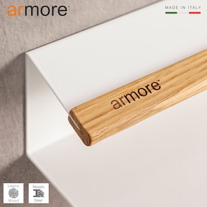 Op de afbeelding: Wit metalen wandrek met een houten arm met het label "armore" in lichtbruin hout. Het rek is gemaakt in Itali&euml;.