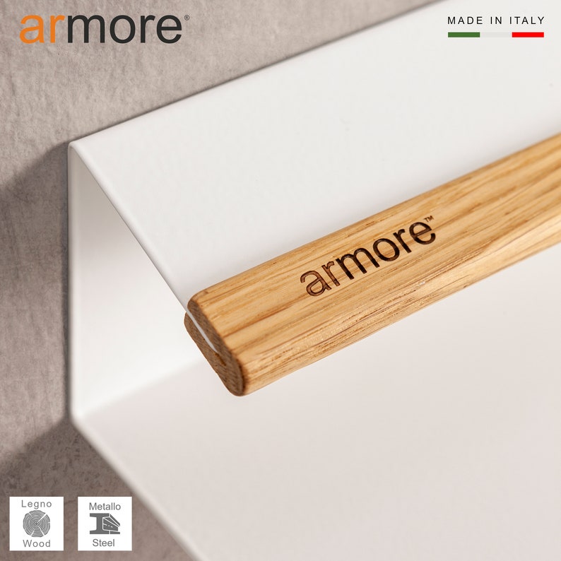 Op de afbeelding: Wit metalen wandrek met een houten arm met het label "armore" in lichtbruin hout. Het rek is gemaakt in Itali&euml;.