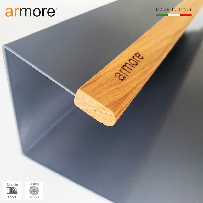Op de afbeelding: Een grijze metalen plantenbak met een houten handvat. Het handvat heeft het woord "armore" erop gegraveerd. De plantenbak is gemaakt van staal en hout. De tekst "MADE IN ITALY" is zichtbaar in de rechterbovenhoek van de afbeelding.