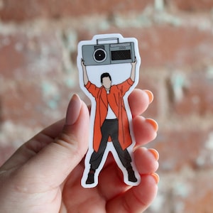 May include: A sticker of a person holding a boombox above their head, with the text "GOOD" on the boombox.
