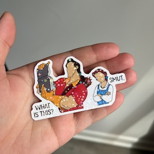 K&ouml;nnte beinhalten: Ein Aufkleber mit einer Cartoon-Illustration von Belle und dem Biest aus dem Disney-Film Die Sch&ouml;ne und das Biest. Das Biest h&auml;lt ein Buch und Belle steht mit verschr&auml;nkten Armen da. Der Text "What is this?" befindet sich unter dem Biest und der Text "Smut." &uuml;ber Belle.