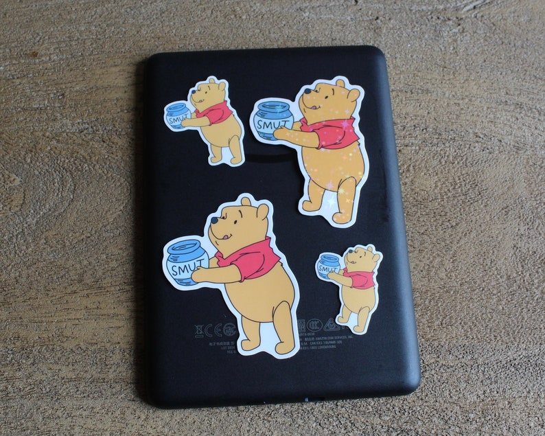 May include: Four Winnie the Pooh stickers on a black background. Each sticker features Winnie the Pooh holding a blue jar with the word "SMUT" on it. The stickers are different sizes and are arranged in a random pattern.