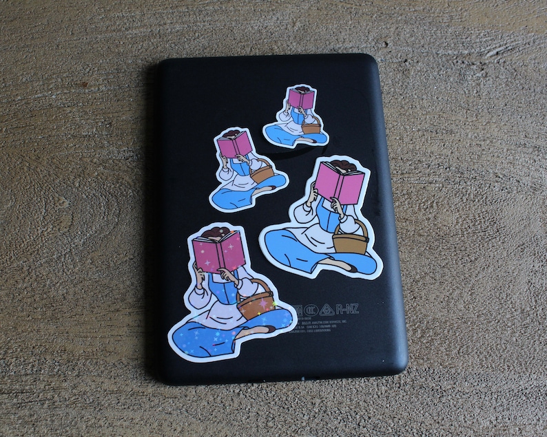 May include: Four stickers featuring a cartoon illustration of a person reading a book. The person is wearing a blue dress and a white apron. The stickers are on a black background.