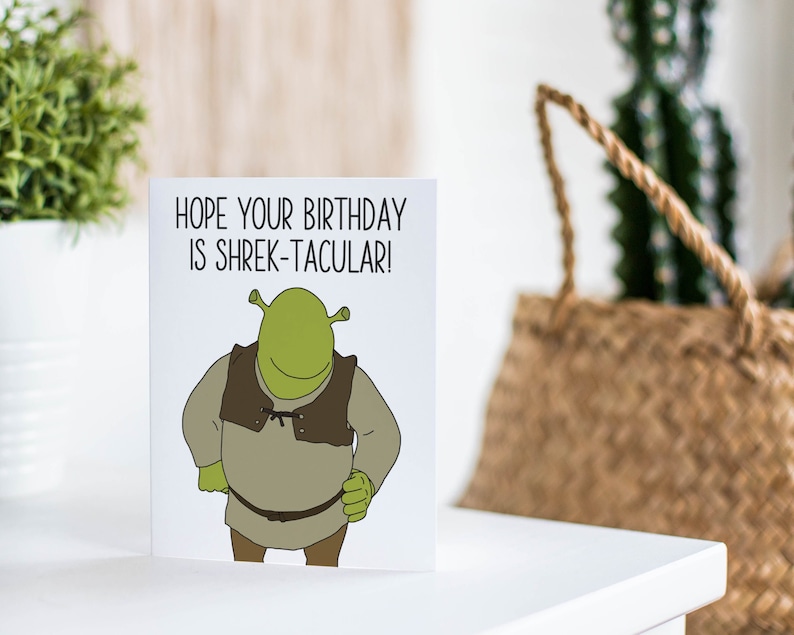 K&ouml;nnte beinhalten: Eine gr&uuml;ne Gru&szlig;karte mit einem Cartoon-Bild von Shrek aus dem Film Shrek. Die Karte lautet "Ich hoffe, dein Geburtstag ist Shrek-takul&auml;r!"