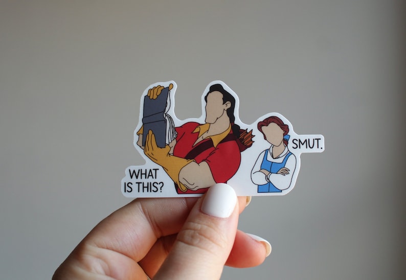 K&ouml;nnte beinhalten: Ein Aufkleber mit einer Cartoon-Illustration von Belle und dem Biest aus Disneys Die Sch&ouml;ne und das Biest. Das Biest h&auml;lt ein Buch und sagt "What is this?" Belle steht mit verschr&auml;nkten Armen da und sagt "Smut."