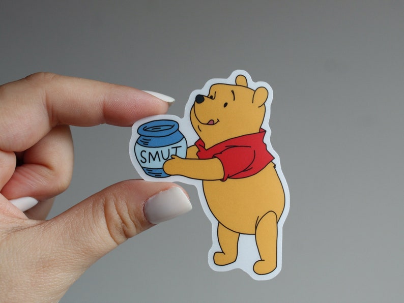 May include: A Winnie the Pooh cartoon character sticker holding a blue jar with the word "SMUT" written on it.