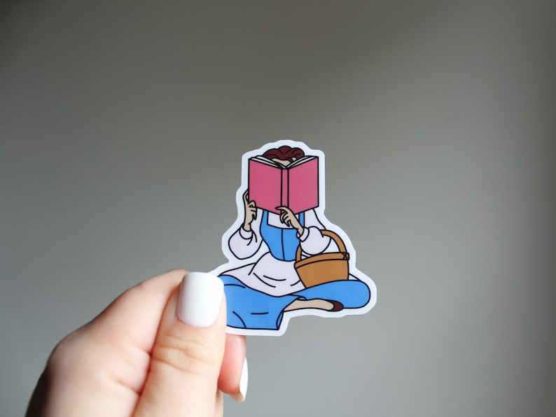 May include: A sticker featuring a cartoon illustration of a woman reading a pink book. She is wearing a blue dress and has a brown basket in her hand. The sticker is on a white background.