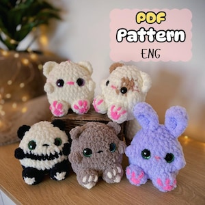 Peut inclure: Patron PDF pour crocheter cinq adorables peluches : un chat blanc, un chat brun, un panda, un ours brun et un lapin violet. Chaque jouet a de grands yeux et des pieds roses.