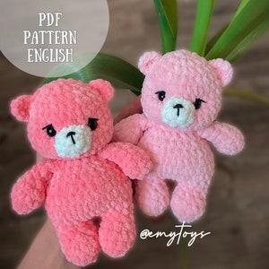 Peut inclure: Deux ours en peluche en crochet rose avec des yeux noirs et des nez blancs. Les ours sont assis sur une main. Le texte "@emytoys" est visible dans le coin inférieur droit de l'image.