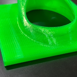 May include: A bright green 3D printed object with a circular opening. The object has a smooth, glossy finish and appears to be made of plastic.