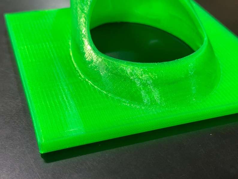May include: A bright green 3D printed object with a circular opening. The object has a smooth, glossy finish and appears to be made of plastic.