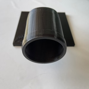 May include: A black plastic pipe fitting with a smooth, cylindrical shape. The fitting has a slightly raised lip around the opening.