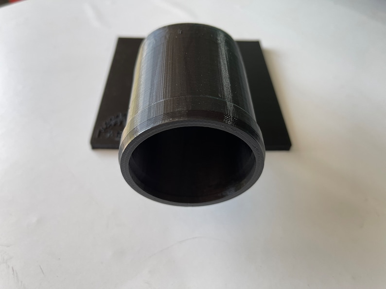 May include: A black plastic pipe fitting with a smooth, cylindrical shape. The fitting has a slightly raised lip around the opening.