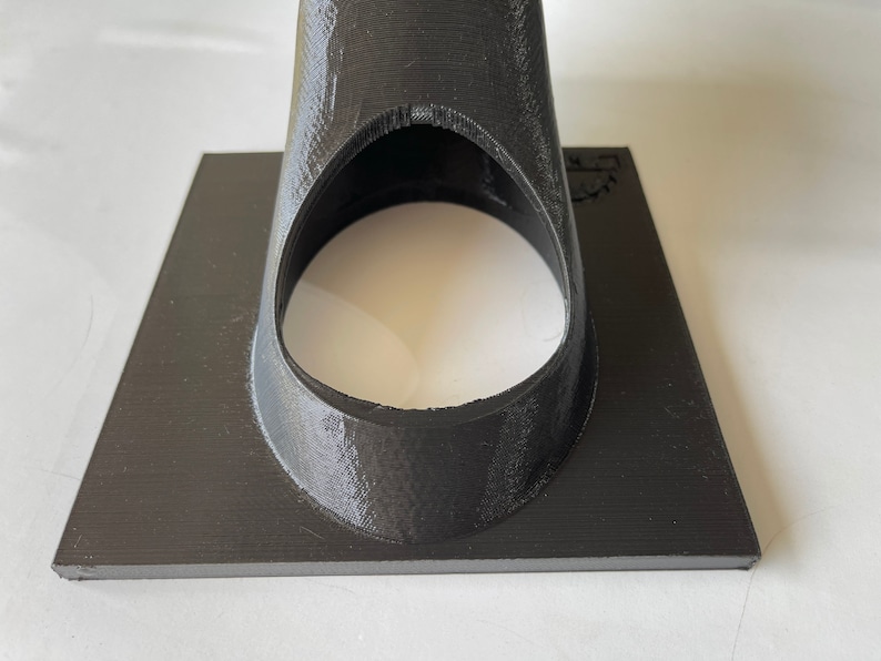 May include: A black 3D printed object with a circular opening. The object has a flat base and a cone-shaped top.