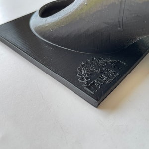 May include: A black 3D printed object with a circular opening and a logo on the base that reads "MakerBot, Designed & Manufactured in the USA."
