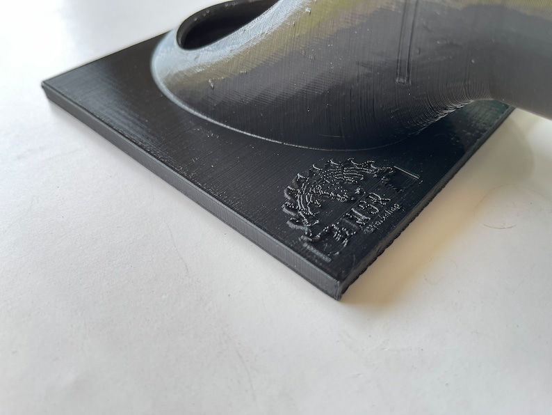 May include: A black 3D printed object with a circular opening and a logo on the base that reads "MakerBot, Designed & Manufactured in the USA."