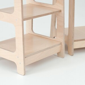 Op de afbeelding: Een houten opstapje met drie planken. De opstap is gemaakt van licht hout en heeft een eenvoudig ontwerp.