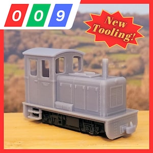 Pode incluir: Uma locomotiva de trem modelo cinza com o texto "New Tooling!" em uma estrela vermelha. A locomotiva tem um design detalhado com janelas, uma chaminé e um para-choque dianteiro. O número "009" é exibido em vermelho, verde e azul.